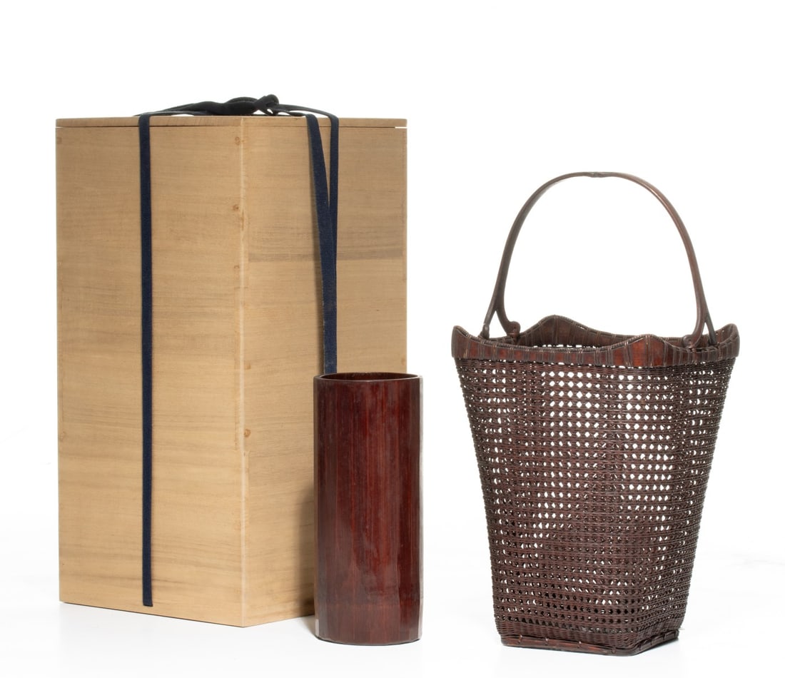 CHIKUUNSAI FLOWER BASKET W/ CARVED HANDLE, ADAIR ESTATE: The dark-lacquered Japanese bamboo flower arranging basket with unusual handle is woven in a crisp openwork plaiting is of tapered squarish form with an open-grid base and a an upper rim is defined by