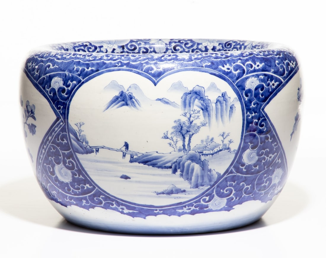 AN EARLY 20C. JAPANESE BLUE & WHITE HIBACHI W/ FIGURES: The large hand painted blue and white porcelain hibachi is decorated with alternating picture windows of figures on a bridge and flowering branches. Measures 12 x 19.5 inches in diameter. Provenance: 
