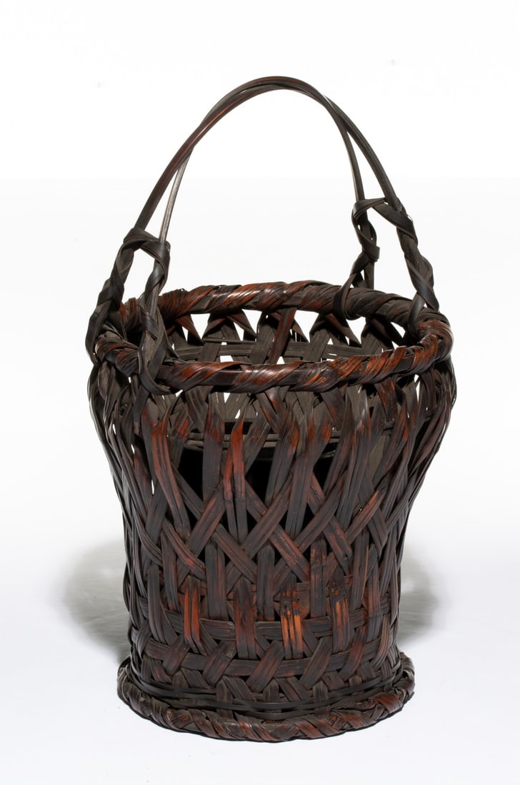 A RUSTIC JAPANESE BAMBOO BASKET, ADAIR ESTATE: The folk tradition hand-woven Japanese bamboo basket is woven using wide, overlapping bamboo splits in an open rustic plaiting style, creating an expressive geometric pattern features a cylindrical bo