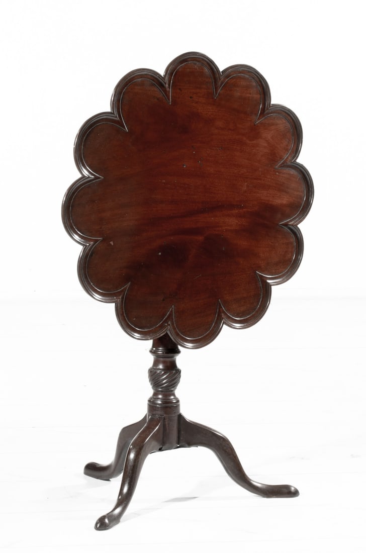 A GEORGIAN SCALLOPED EDGE MAHOGANY TILT-TOP TABLE: The top with twelve relief-carved scallops with tilt-top mechanism is mounted on a turned vase raised on three cabriole legs. Measures 28H x 28 inches in diameter. Tilted height is 42.5 inches. Proven