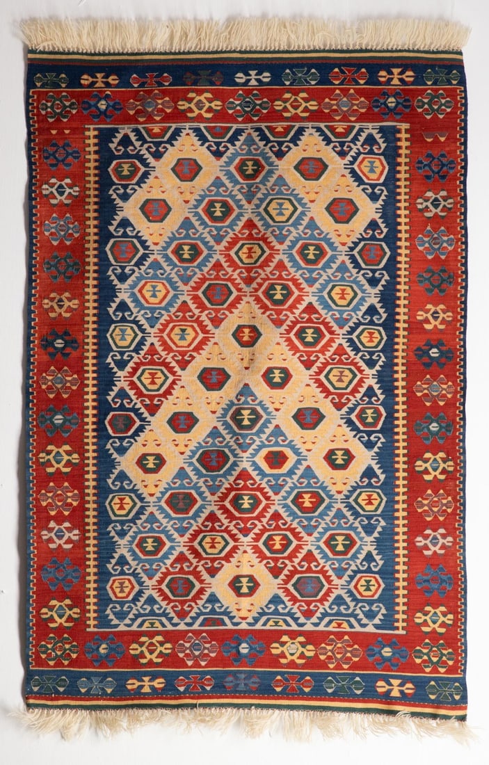 A MODERN TURKISH KILIM, CENTRAL TURKIYE: The blue field with allover offset rows of interlocking pastel stepped rhombus pole medallions within a terracotta border enclosing continuous flower heads. Measures approximately 67 x 45 inches; 5ft.