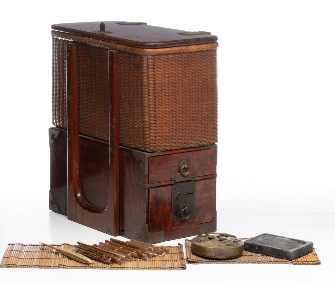 A JAPANESE KEYAKI WOOD AND WICKER FISHERMAN'S BOX: The creel and box combination is found with a few accoutrements that include an inkstone and brass burner, but also a tenkara line holder. Measures 8 x 7.5 x 14.5 and 9.25 x 16 x 8 inches. Provenance: