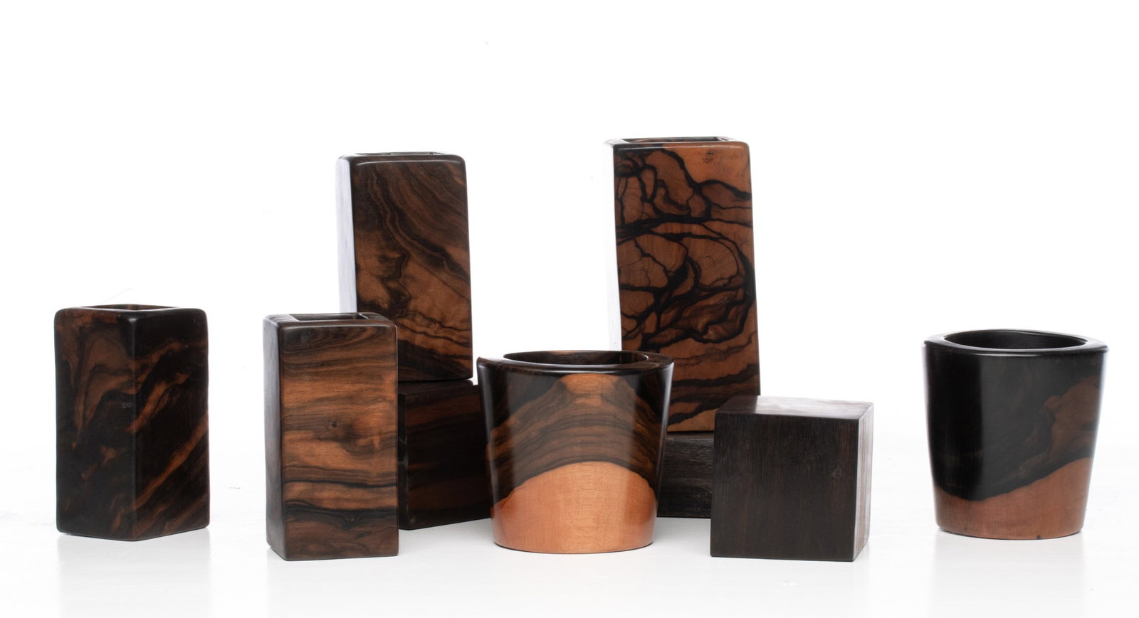A COLLECTION OF EBONY WOOD ARTICLES: Carved and polished ebony wood cups, blocks and vases. Sizes range from 3.5 x 3.5 x 3.5 to 7.75 x 3.75 x 3.75 inches. Provenance: The estate of John Adair Jr. (1942-2025), founder and proprietor of Ku