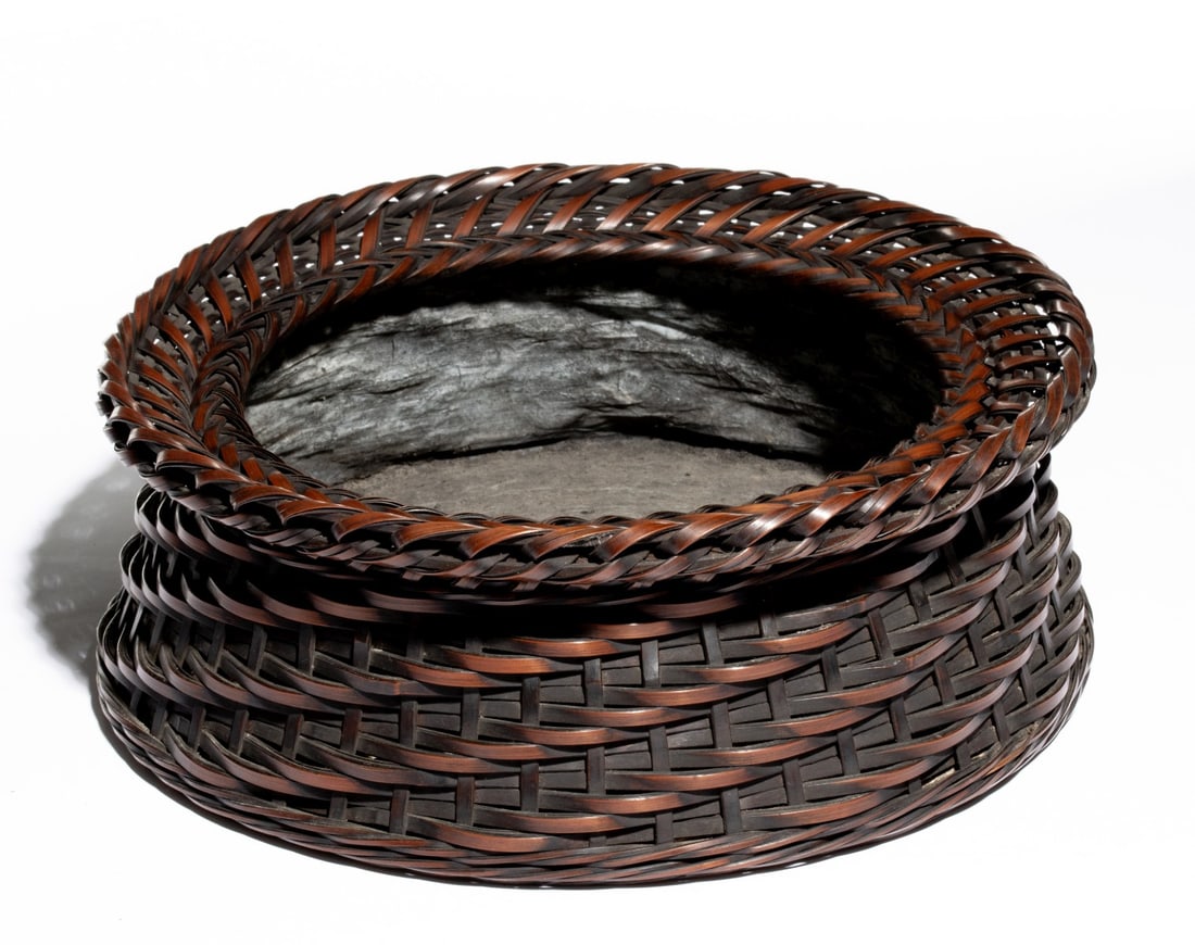 AN ARTIST SIGNED JAPANESE BAMBOO CHARCOAL BASKET, ADAIR: The circular basket of twill weave plaiting is lined in coated washi paper, signed by an unidentified artist on the base slat. Measures 4 x 11 inches in diameter. Provenance: The estate of John Adair 
