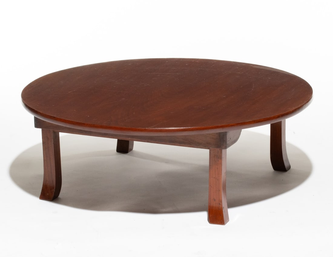 A LOW JAPANESE KEYAKI WOOD TABLE WITH FOLDING LEGS: Measures 11 x 32.5 inches in diameter. Provenance: The estate of John Adair Jr. (1942-2025), founder and proprietor of Kurofune Antiques in Tokyo (est. 1978), a world-renowned destination for Japanese