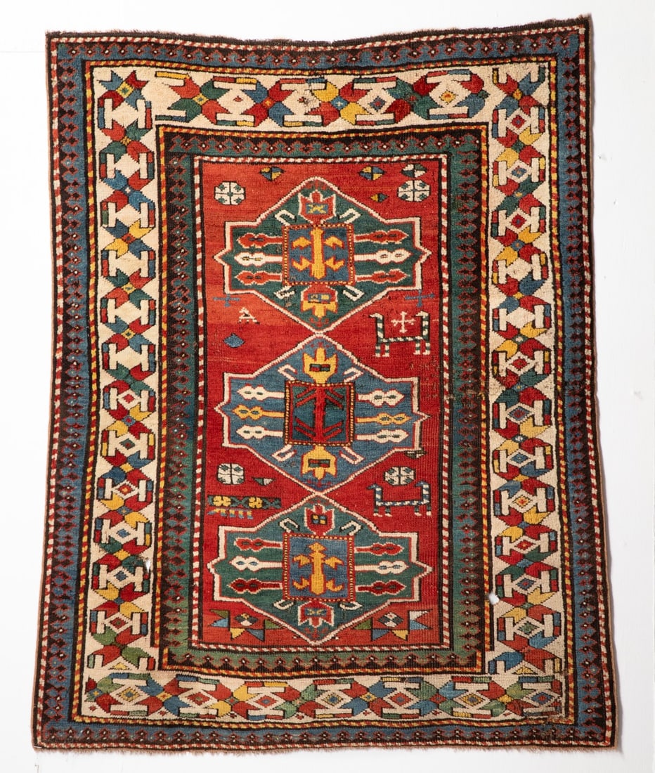 A LATE 19TH CENTURY WEST CAUCASUS KAZAK RUG, AS FOUND: The red field with three pointed cartouche medallions, supported by two headed animals and flower heads, within an ivory polychrome star and linked bracket vine border, reciprocal trefoil minor guard 
