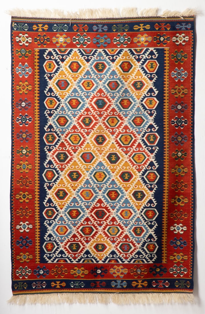 MODERN TURKISH KELIM, CENTRAL TURKIYE: The blue field with allover rows of pentagonal medallions within a pole vine lattice, within a terracotta border enclosing continuous polychrome flower heads, horizontal banded blue ends. Measures app