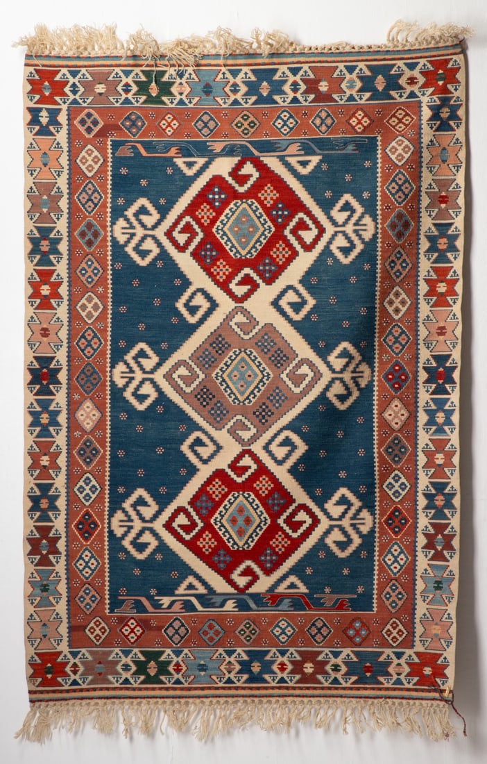TURKISH KELIM, CENTRAL TURKIYE, MODERN: The blue hooked and stepped field with a column of three pin wheel hooked medallions, within an ivory continuous butterfly flower head border. Measures approximately 69 x 44 inches; 5ft.9 inches x 3ft