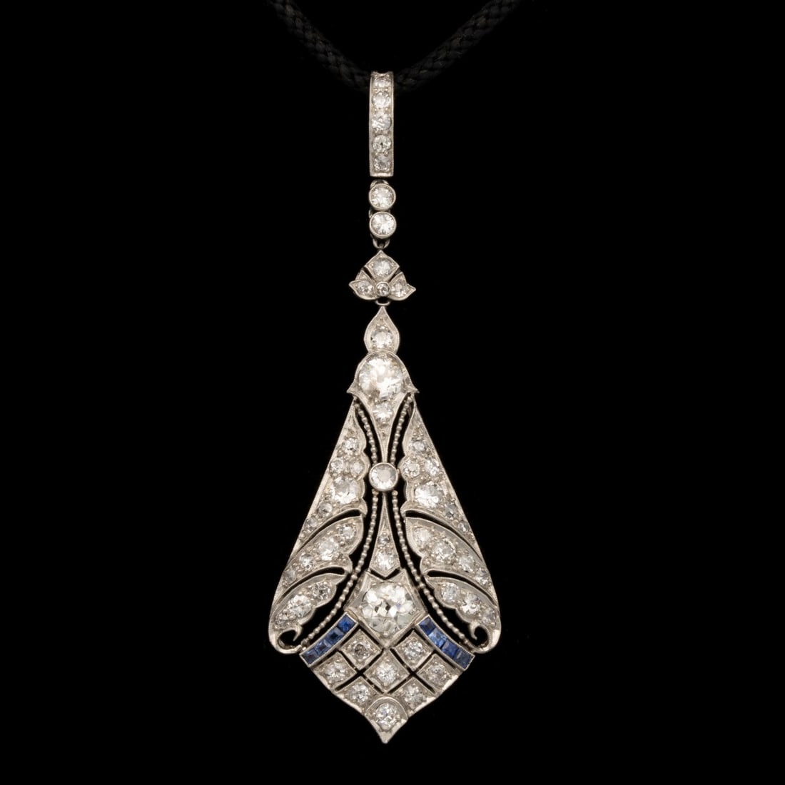 A FINE EARLY 20C DIAMOND AND SAPPHIRE LAVALIER PENDANT: The unmarked platinum lavalier pendant is set with 44 old European cut diamonds and 8 square-cut blue sapphires. Pendant measures 2.75 x 1 inch and weighs 8 grams. Without proof of exemption, be aware
