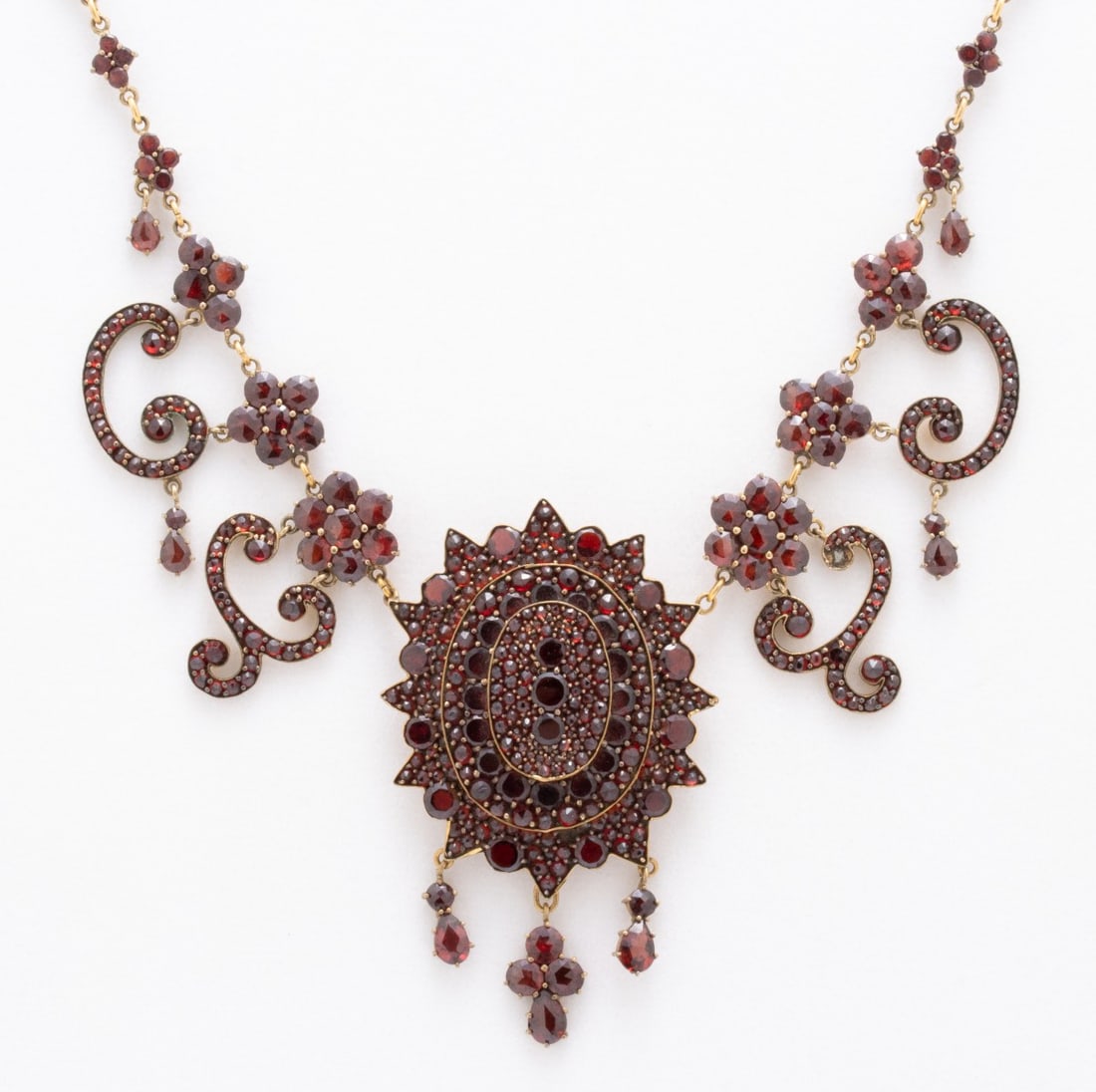 AN ELEGANT VICTORIAN BOHEMIAN GARNET NECKLACE: An exceptional example with an elaborate drop and garnet clusters the full length of the chain and on the clasp. One missing stone. Necklace length measures 17 inches, pendants is 2.75 x 1.5 inches.