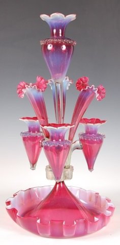 UNUSUAL AND ELABORATE 20-INCH RUBINA VERDE EPERGNE: A large and elaborate six lily epergne with a large central stem topped by a cranberry vase that has clear applied rigaree at the shoulder and an opalescent petal shaped rim. The main shaft of that ce