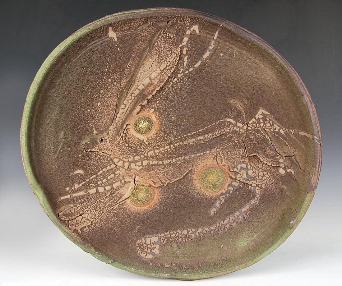 KENFERGUSON (1938 - 2005) STUDIO POTTERY CHARGER WITH: A high fired stoneware charger with running hare in relief and bursts of thick green glaze inspired by the fruit of the Osage Orange tree, according to a conversation between the owner and the artist 