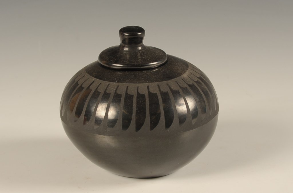 SAN ILDEFONSO POTTERY: A lidded jar with repeating feather design signed under the vase. Measures 4 x 4.5 inches.