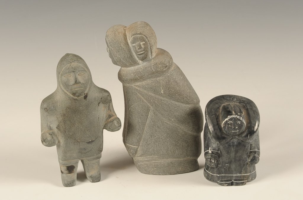 THREE INUIT CARVED STONE FIGURES: The smallest being signed Vavutak. The sizes range from 6 inches down to 5 inches in height.