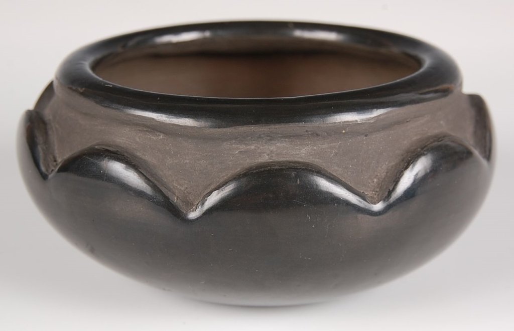 BLUE CORN SAN ILDEFONSO POTTERY: A low bowl signed under the base and decorated with a deep carved rim. Measures 2.75 x 5.5 inches.