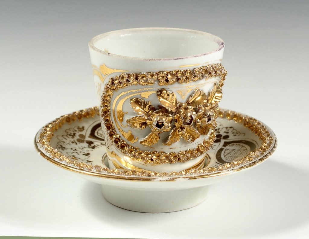 RUSSIAN (?) PORCELAIN CABINET CUP AND SAUCER SET: The cup having an unglazed top rim and applied florals. The base is unmarked except for two scratched symbols. The deep-well saucer is unmarked as well. Cup measures 3.75 x 4.25 inches, and saucer mea