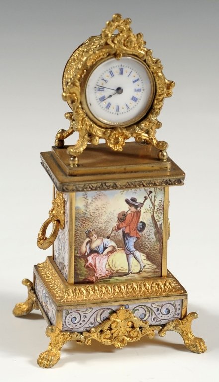 FRENCH ORMOLU CLOCK WITH ENAMELS: A small windup clock with enamel dial and rococco frame, gold metal mounts and eight fine enamel panels including courting scenes with 18th century characters. Measures 4.75 x 2.5 inches.