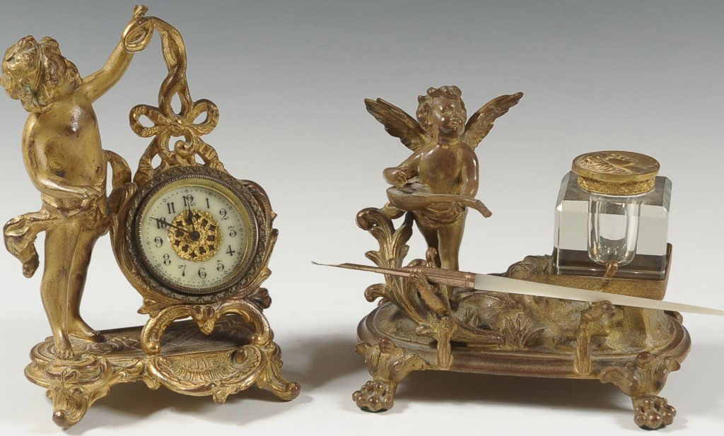 TWO CUPID FIGURAL DESK PIECES: INKWELL AND CLOCK: Footed inkwell with figural cupid behind pen stand and beside inkwell, plus a cupid figural novelty clock by The New Haven Clock Company. Inkwell measures 5.5 x 6 inches, and clock measures 6.5 x 5 in