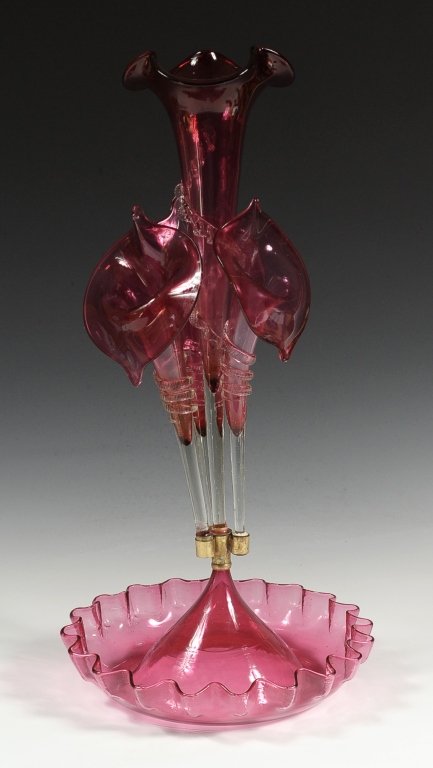 VICTORIAN 21 INCH CRANBERRY EPERGNE: Three lilies surrounding a central lily, all with applied clear glass rigaree on cranberry glass. Measures approximately 21 x 10 inches in diameter.