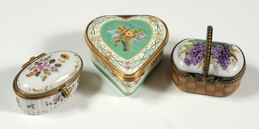THREE PORCELAIN AND ENAMEL BOXES: Including a heart shaped Halcyon Days box, along with a Limoges basked-shaped box, and a third oval French porcelain box. All but the last are late 20th century. Three pieces that range in size from .
