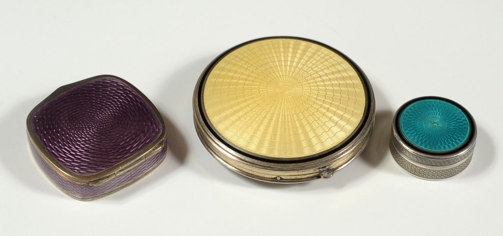 THREE STERLING SILVER COMPACTS W/ GUILLOCHE ENAMEL: Each with markings to indicate sterling silver, and each with guilloche enamel decoration. The two round examples each have engine-turned designs on the reverse side. The middle example has European h