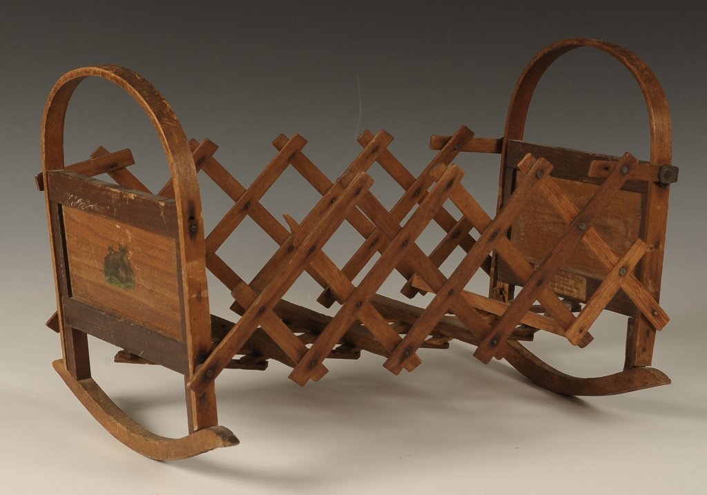 AN UNUSUAL PATENTED FOLDING DOLL CRADLE, FENNER 1881: An unusual collapsible cradle with bent wood head and foot board, decal decoration on each end and original paper label with patent information C.A. Fenner Mystic River, Conn. Measures 10.5 x 16 x 9.5