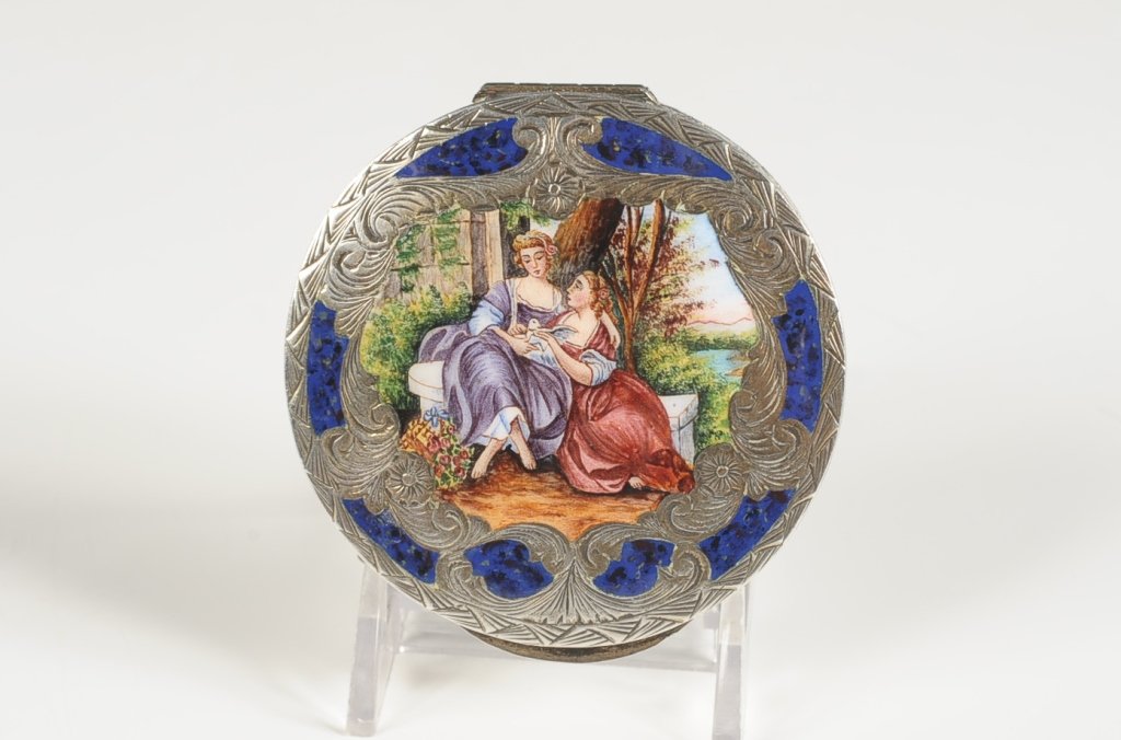 CHAMPLEVE COMPACT WITH A VERY FINE PAINTED SCENE: Chased silvertone compact with blue champlevÃ© enamel and a very finely hand painted scene of women with a dove, framed mirror in the lid, puff, unmarked, measures 3 inches.