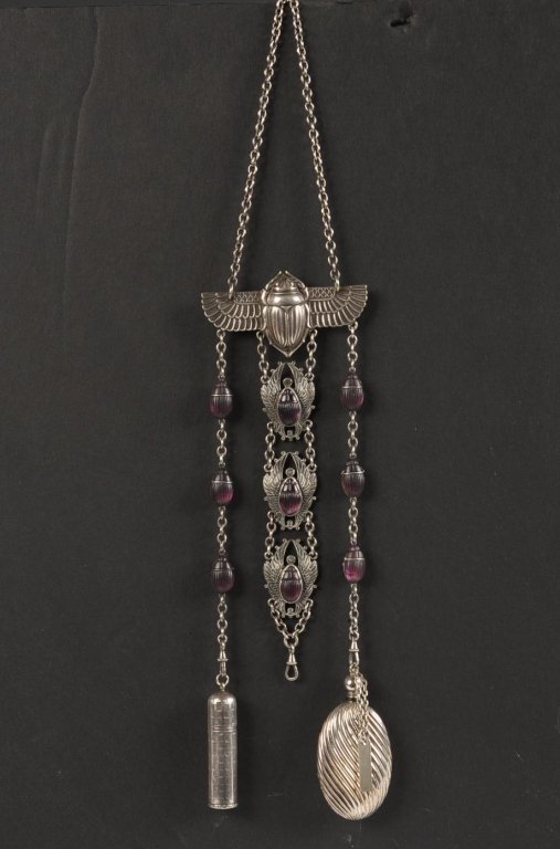 .800 SILVER CHATELAINE W AN EGYPTIAN SCARAB MOTIF: .800 silver vanity chatelaine with chain, brooch pin with a scarab, three dangles with amethyst jewels, lipstick and a perfume flask, center dangle with three jeweled scarabs is missing its item, mark
