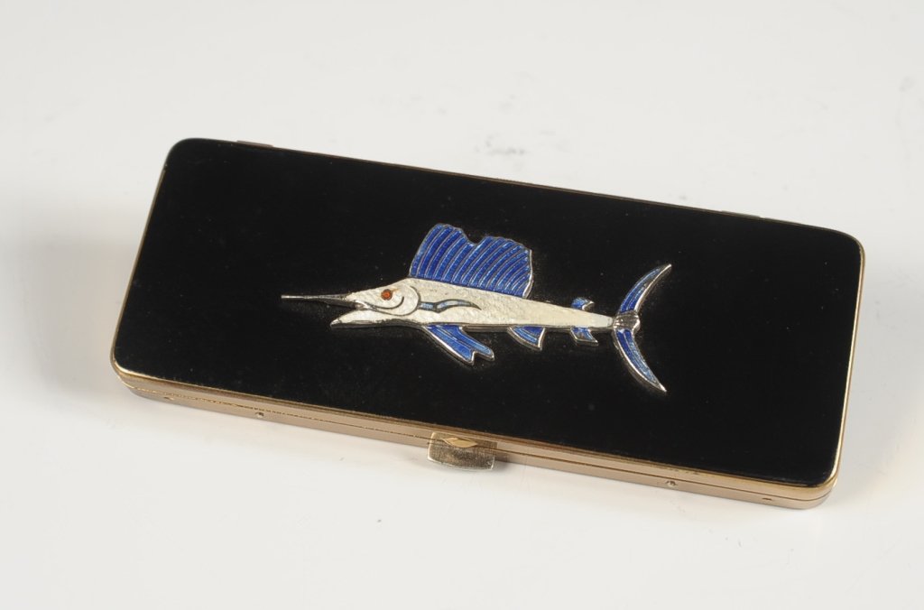 VOLUPTE VANITY CASE WITH ENAMELED SWORDFISH: Black enameled vanity case with an enameled swordfish design on the lid, original branded gift box and felt sleeve, polished metal mirror in the lid over a storage compartment, lidded wells for powder