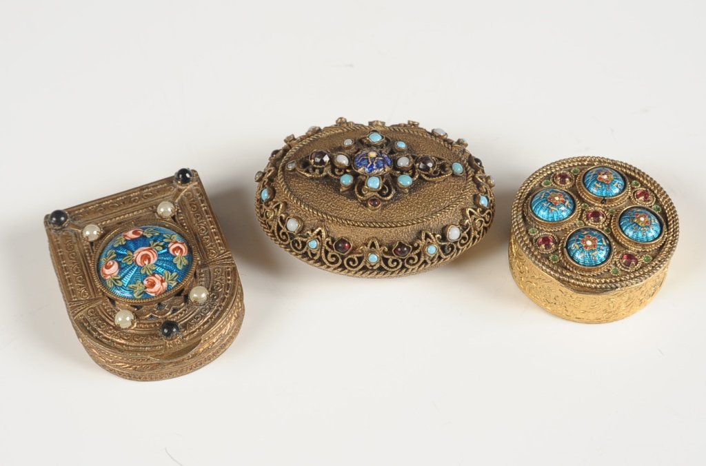 THREE SMALL JEWELED & FILIGREE GOLDTONE COMPACTS: Goldtone jeweled filigree over foil compact with guilloche center with enameled roses, framed and beveled mirror in the lid, mesh sifter and puff, French, marked on the bottom, measures 1.75 x 1.375 i
