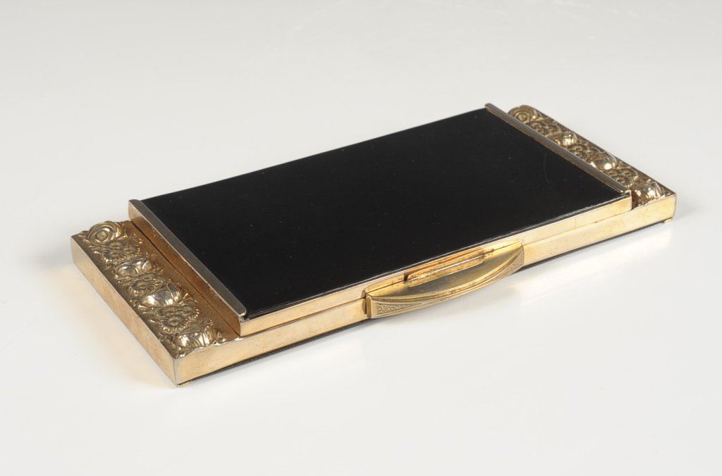 LARGE EMBOSSED VANITY CASE FROM ARGENTINA: Goldtone vanity case with embossed roses and black plastic, mirror in the lid, sectioned plastic base with one hinged well, hinged metal comb holder over the mirror marked 'Industria Argentina', measu