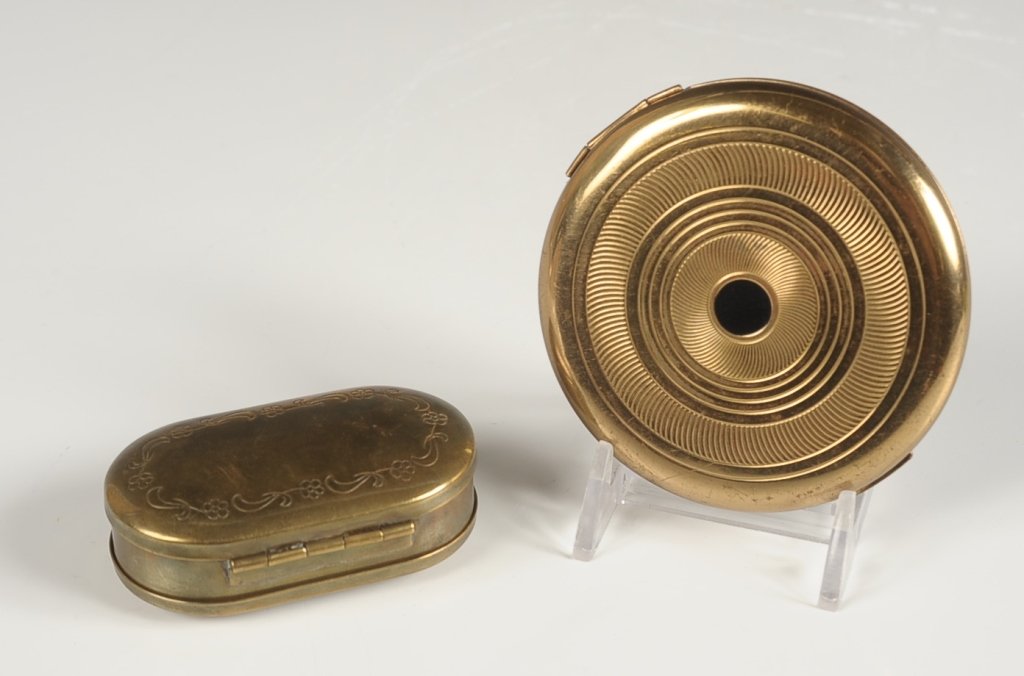 COTY DUO COMPACT, AND AN OVAL DOUBLE-SIDED COMPACT: Coty goldtone with black enamel duo compact with a polished metal mirror over the rouge well in the lid with pan and puff, base holds a powder well with a hinged lid and branded puff, marked on the po