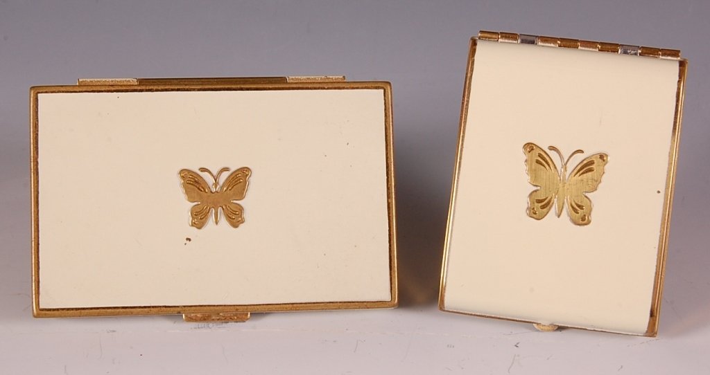 TWO LUCRETIA VANDERBILT COMPACTS W BUTTERFLIES: Cream enamel with goldtone butterfly duo compact with a polished metal mirror over a rouge well in the lid with pan and puff, hinged powder well in the base with a puff, marked on the inside base, mea