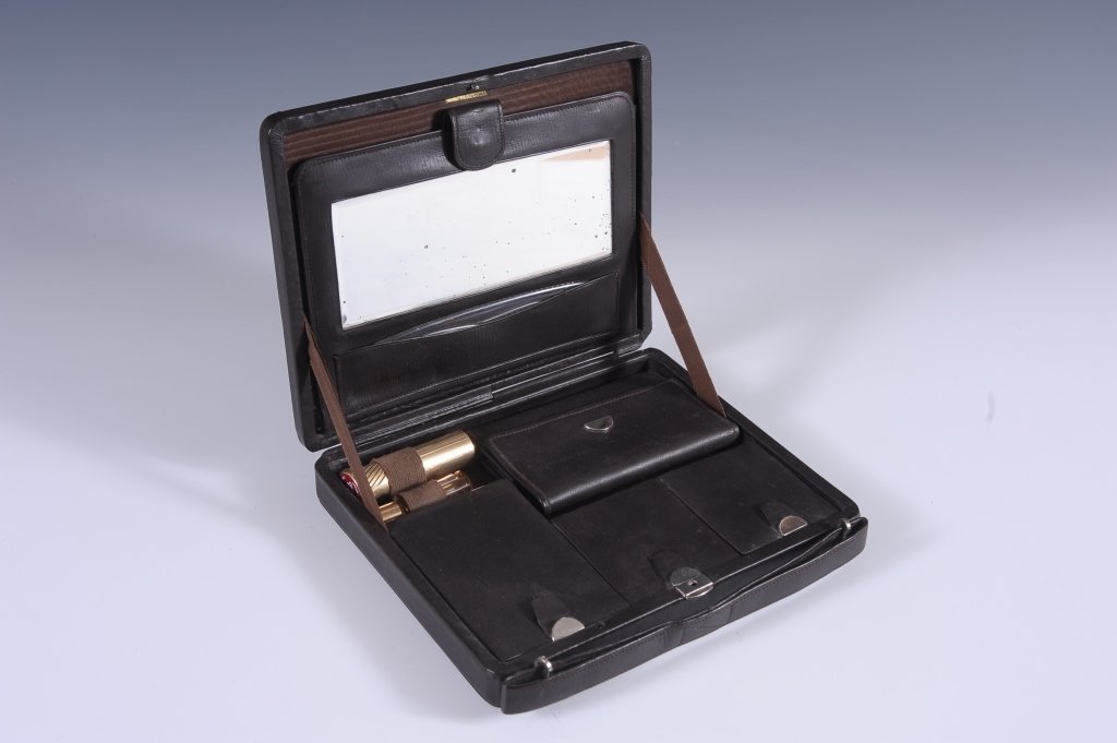 LEATHER TRAVEL VANITY CASE: Monogrammed 'PCS' on the top, leather interior with snap compartment with mirror and comb pocket, base holds a small purse, three hinged wells, Coty lipstick and a Lancomb perfume, measures 6 x 7.5 in