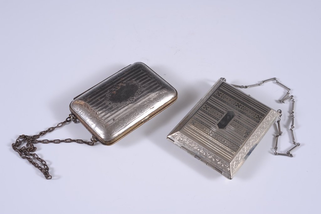 TWO MINIAUDIERE CASES: Silvertone miniaudiÃ¨re with an 8 inch chain handle, hinged cigarette compartment in the lid, base holds a hinged rouge compartment with two lipsticks, rouge pan and a puff, rotary powder well, unma