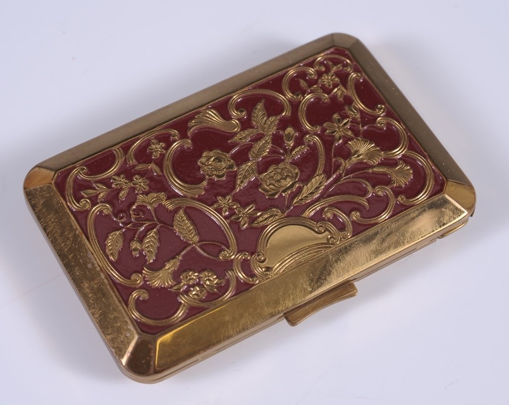 RICHARD HUDNUT VANITY CASE IN ORIGINAL PRESENTATION BOX: Goldtone vined florals with red enameling vanity case compact with a framed mirror in the lid, the base holds a peek-through lipstick in one side, rouge well with pan and branded puff, and a hinged po