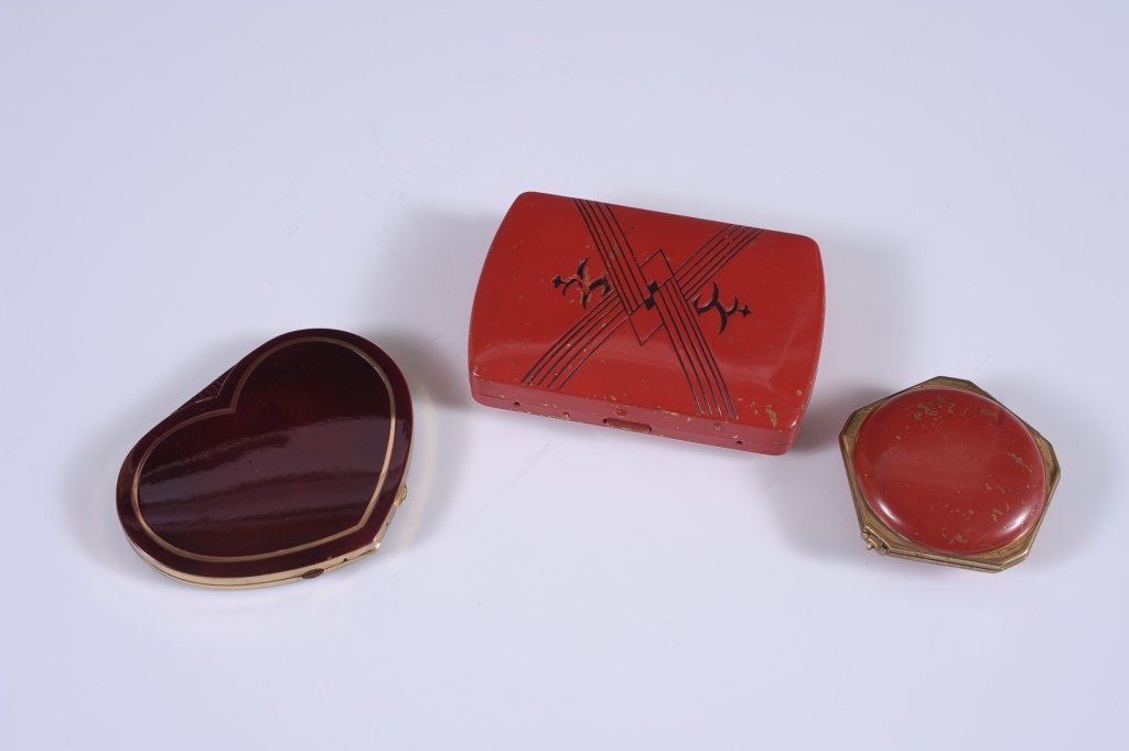 RED ENAMEL MINIAUDIERE & TWO RED ENAMEL COMPACTS: MiniaudiÃ¨re in red and black enamel with a cigarette compartment in the lid, hinged mirror in the base over powder and rouge wells with pans and puffs and a lipstick in its own well, unmarked, 3.25