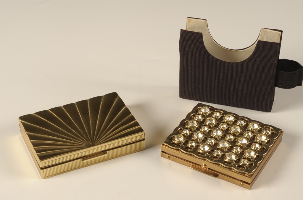 EVANS AND FIFTH AVENUE VINTAGE COMPACTS: Fifth Avenue compact with filigree and crystals on the lid, with faille slip case with an elastic holder for a lipstick (none present), beveled mirror in the lid, branded puff in the base, measures 2.