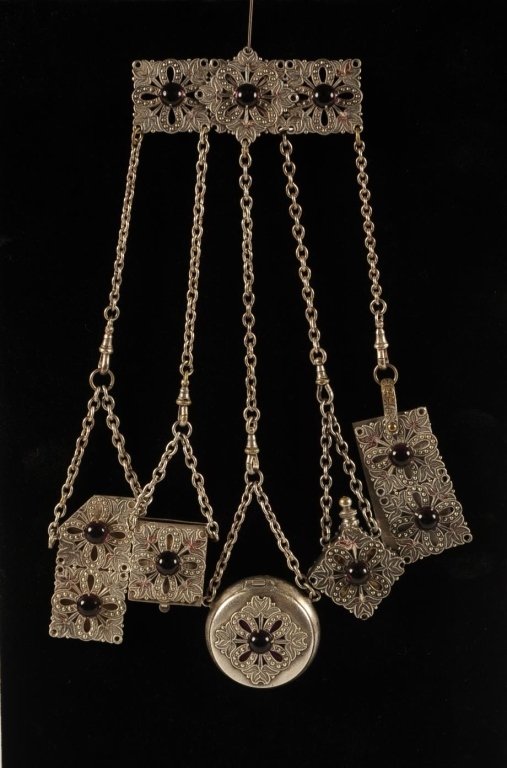 CHATELAINE BROOCH WITH FILIGREE: Silvertone filigree brooch and chatelaine accessories with amethyst colored glass cabochons, includes a notepad, perfume flask, compact, stamp holder and comb holder, unmarked, measures 9 inches.