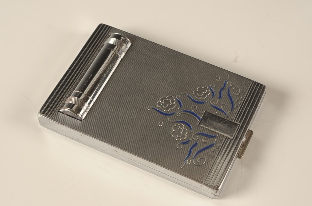 BOURJOIS EVENING IN PARIS VANITY CASE: Silvertone vanity case with peek through lipstick, polished metal mirror in the lid, rouge well and hinged powder well in the base with pan and branded puffs, marked on the bottom, measures 3.5 x 2.25