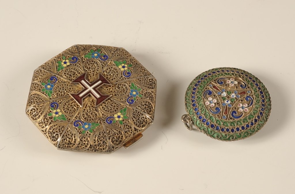 TWO ENAMELED FILIGREE COMPACTS: Goldtone filigree compact with an enameled cross on top, framed mirror in the lid, powder well with puff and pan with original French label on the bottom, small hallmarks on the catch, measures 2.5 in