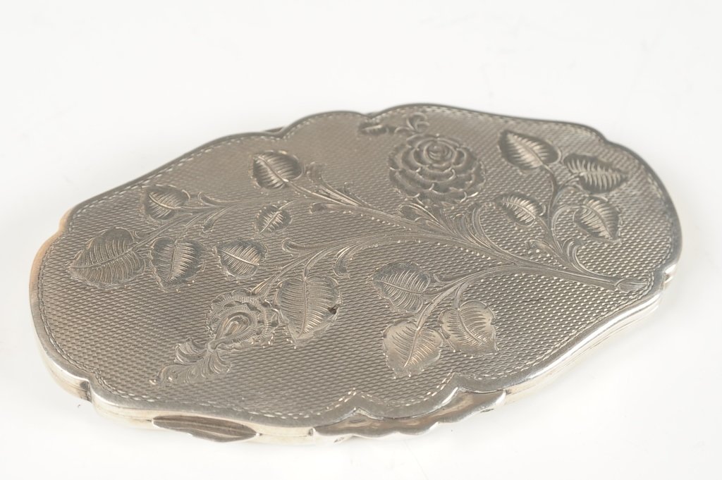 AUSTRIAN STERLING HAND CHASED COMPACT: Oval compact with a hand chased floral design on the top, framed mirror in the lid, base holds a mesh sifter, marked on the outer rim near the catch, measures 3.75 x 2.25 inches.