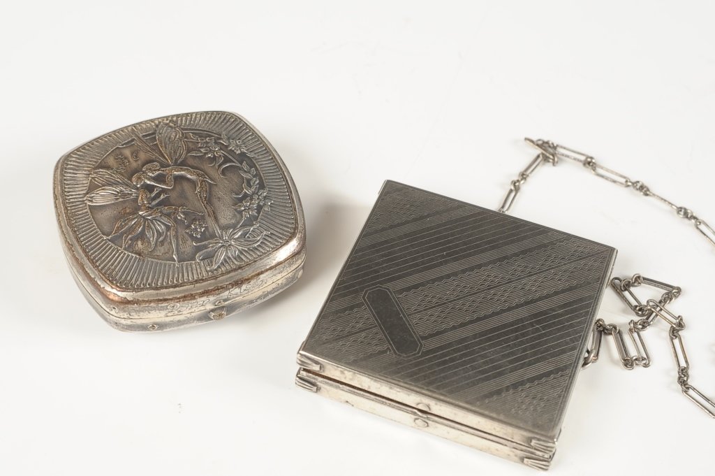 1925 DJER KISS FAIRIES COMPACT, PLUS A DUO COMPACT: Djer Kiss silvertone compact with a Art Nouveau scene of kissing fairies embossed on the top, rouge well in the lid with pan, a hinged double sided mirror on top, base holds a powder well with pan, ma