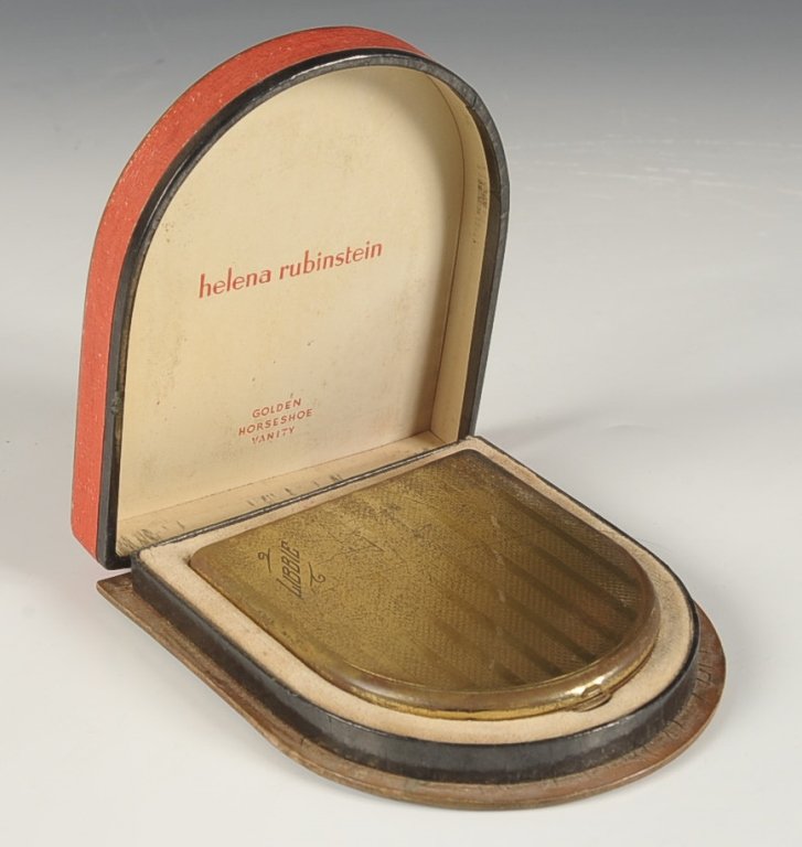 HELENA RUBINSTEIN VANITY CASE IN ORIGINAL PRESENTATION: Original presentation box branded 'Golden Horseshoe Vanity' with a goldtone vanity case, monogrammed 'Libbie' on the top, framed mirror in the lid, hinged wells for lip rouge, rouge and powder, pans f