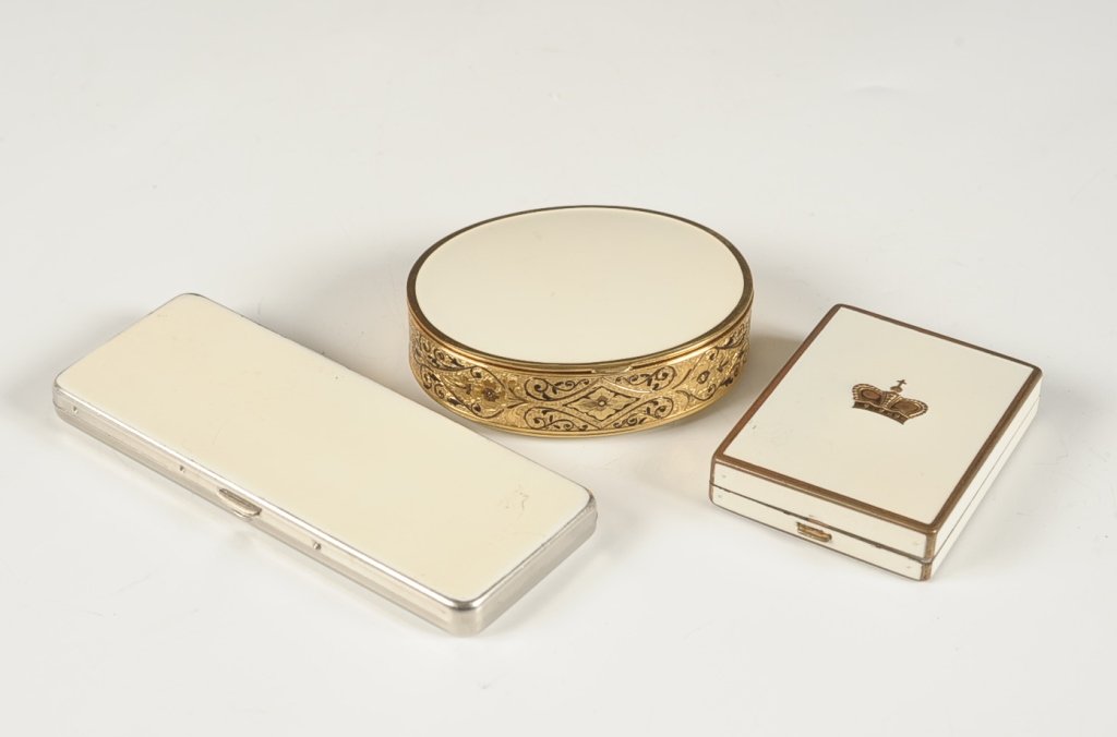 WHITE ENAMEL PRINCE MATCHABELLI, VOLUPTÃ‰ & ANOTHER: Prince Matchabelli white enamel and goldtone duo compact with a crown on top, hinged metal mirror over a rouge well in the lid with pan and branded puff, sliding powder dispenser in the base with puff