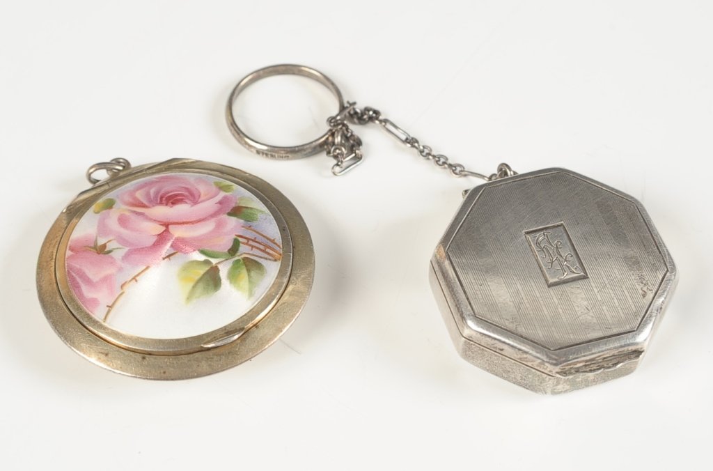 TWO STERLING COMPACTS, ONE WITH AN ENAMEL ROSE: Sterling pendant compact with an enameled rose on top, framed mirror in the lid, marked in the base, measures 1.75 inches, weighs .75 ozt. Plus a sterling compact with chain handle and finger ring, fr