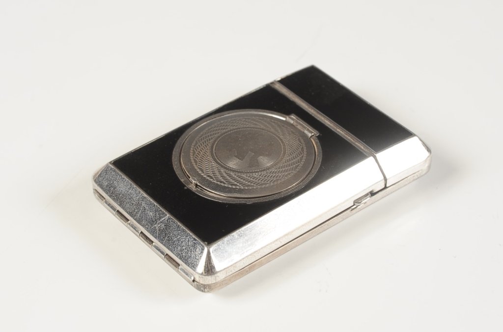 TERRI BLACK ENAMEL VANITY CASE: With etched dancers on top, powder well on top with mirrored lid and mesh sifter, hinged doors open to a rouge well with pan and branded puff, other side with blotting paper and a branded lipstick wit