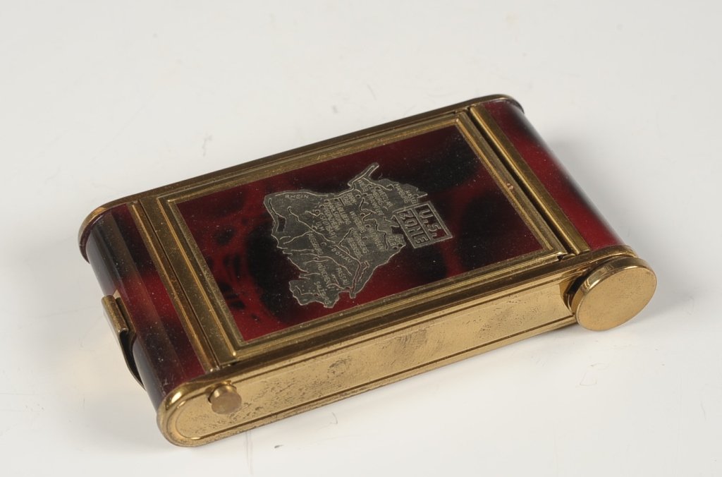 CAMERA STYLE VANITY CASE W MAP OF POST WWII GERMANY: Goldtone case with dark red enameling, silvertone map of Germany marked 'U.S. Zone' on the top, external lipstick, bottom compartment holds a manicure set, other side is a pop up lid with a mirror and