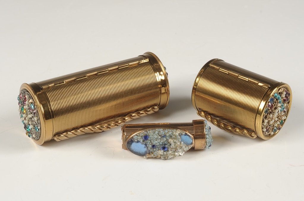 TWO BOLSTER-SHAPED COMPACT & PURSE W JEWELED ENDS: Plus a jeweled lipstick case with a foldout mirror, unmarked, measures 2.5 inches when folded. Goldtone bolster shaped compact and purse with jeweled ends, compact has a mesh sifter, unmarked, measure