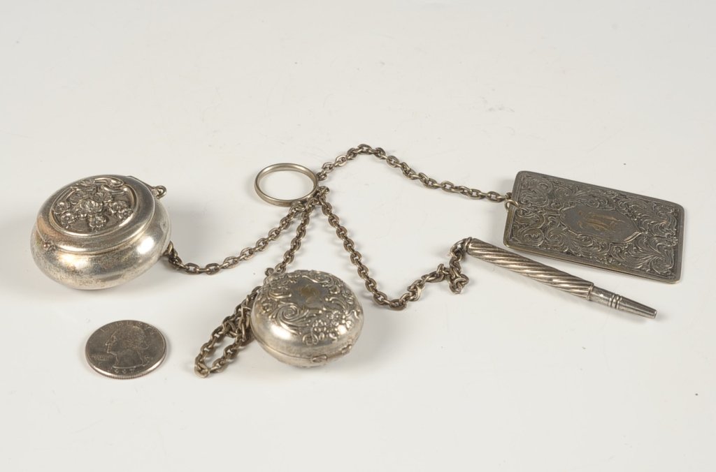 EMBOSSED CHATELAINE WITH FINGER RING: Four chains with compact, perfume, notepad and mechanical pencil, monograms throughout, unmarked, pieces measure from 1.25 to 2.75 inches, overall length of 9 inches.